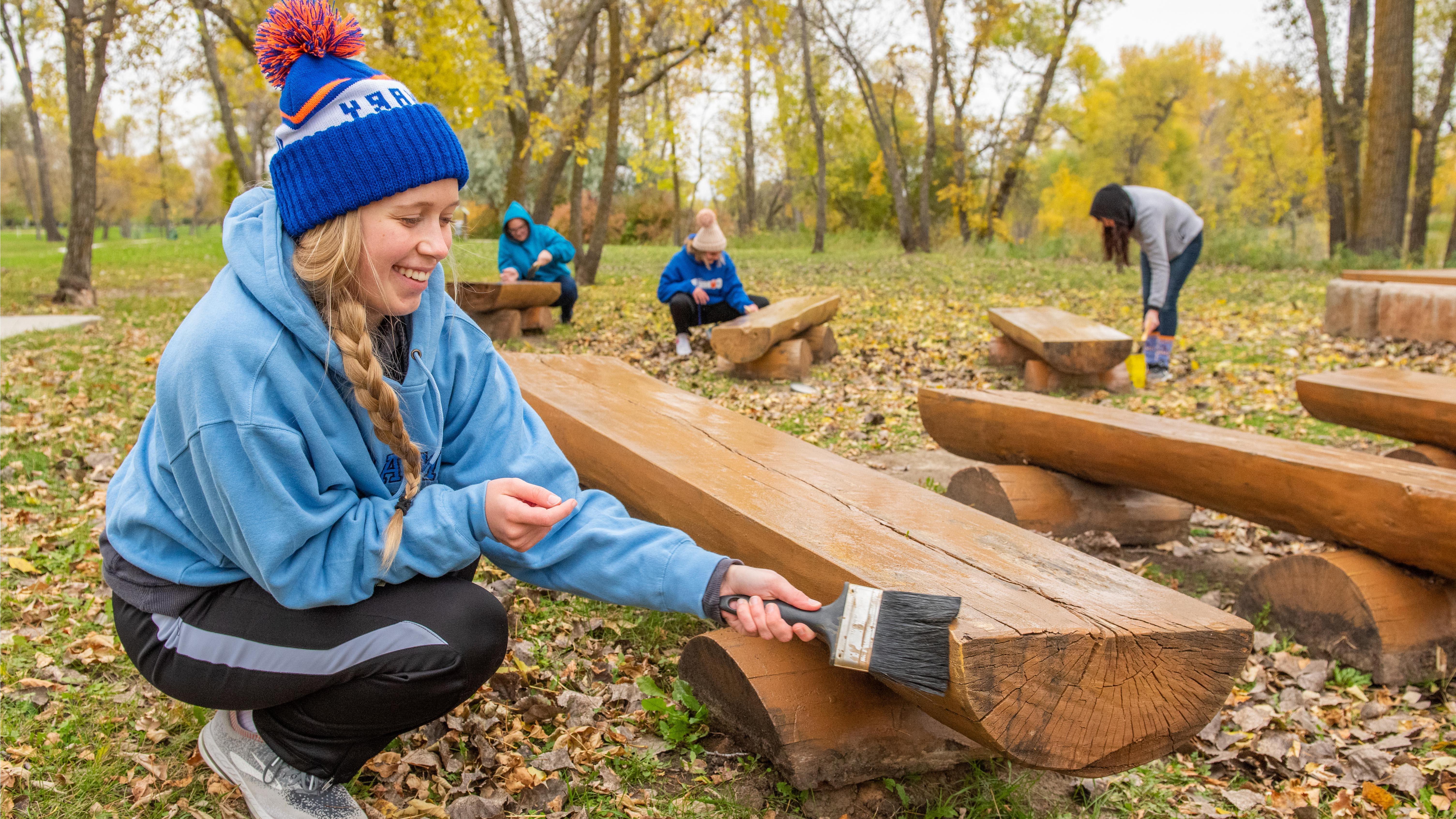 Female student painting a bench during day of service.